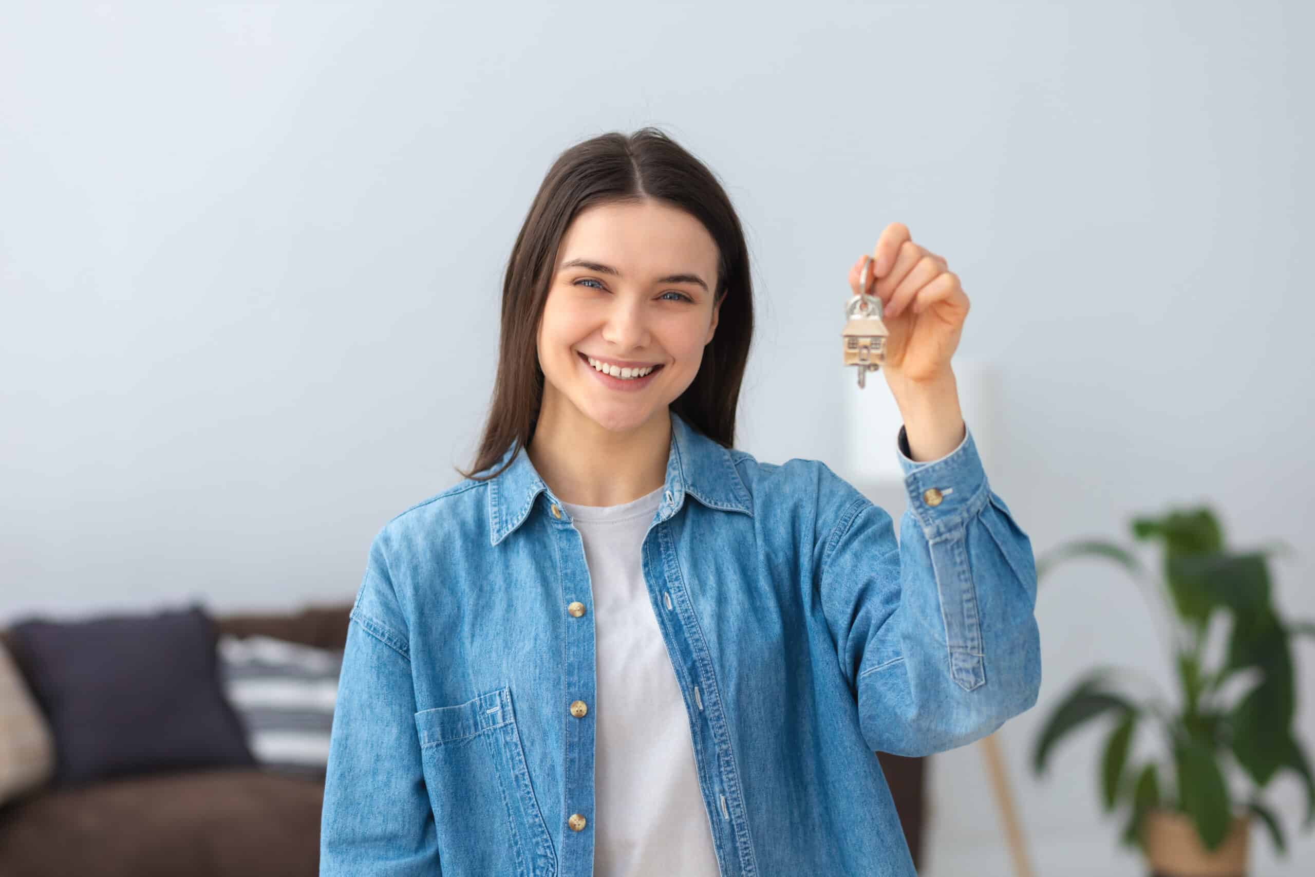 Young handsome young caucasian woman holding keys of new home and friendly smiling happy looking at the camera Woman holding keys scaled